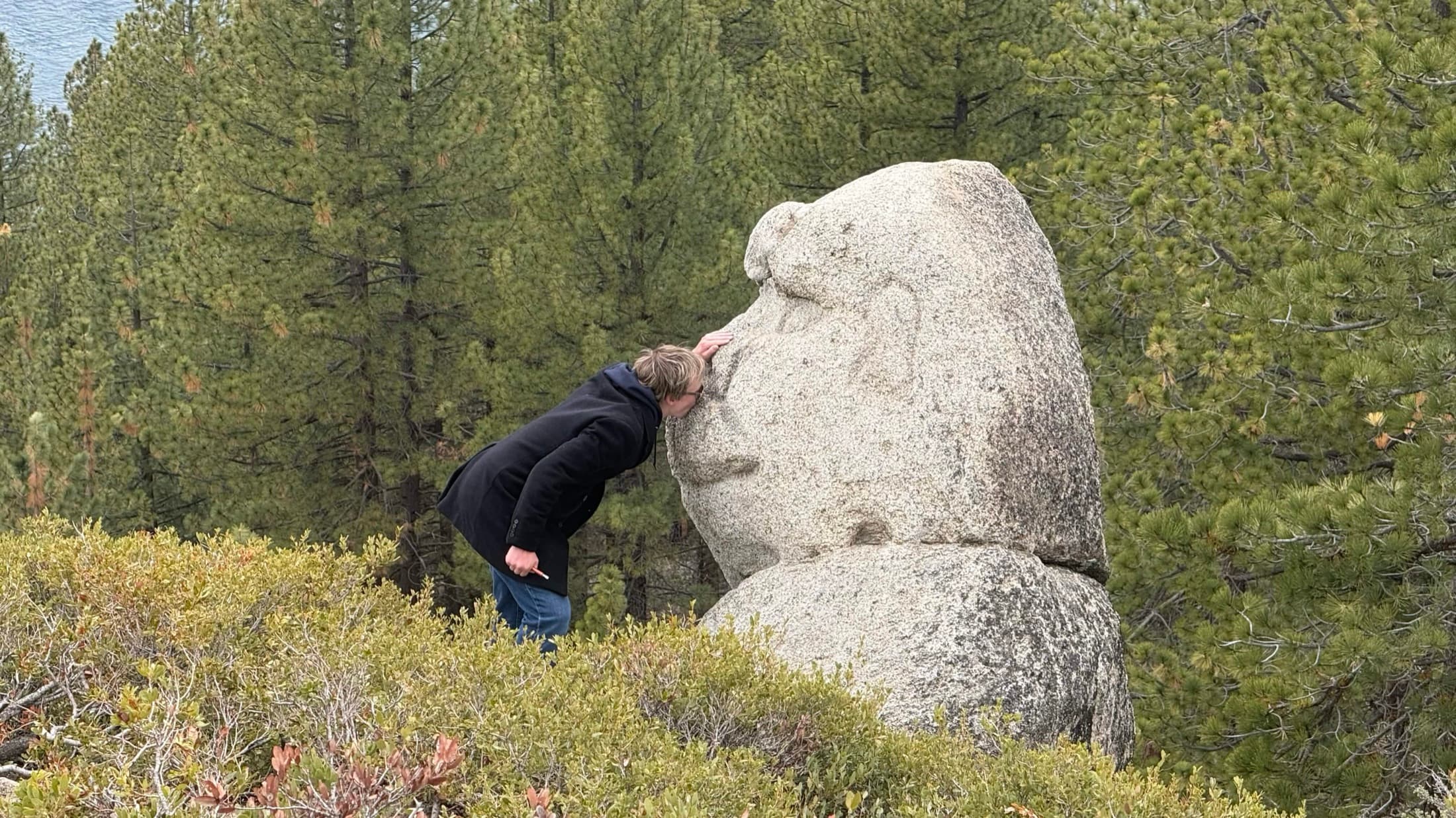 A chapter member beside a large rock during an outdoor trip