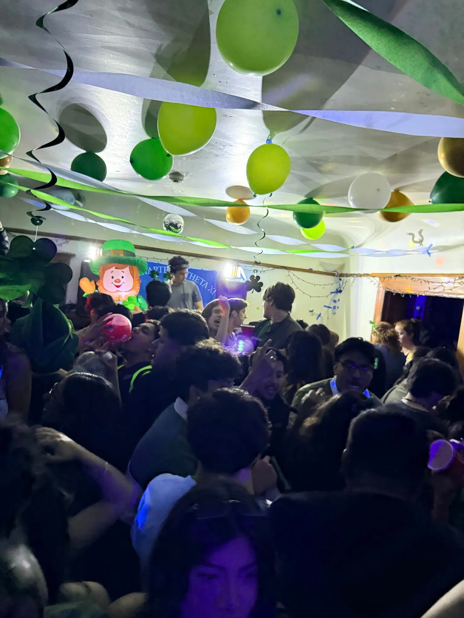 Chapter members at a cocktail night beneath blue and yellow balloons