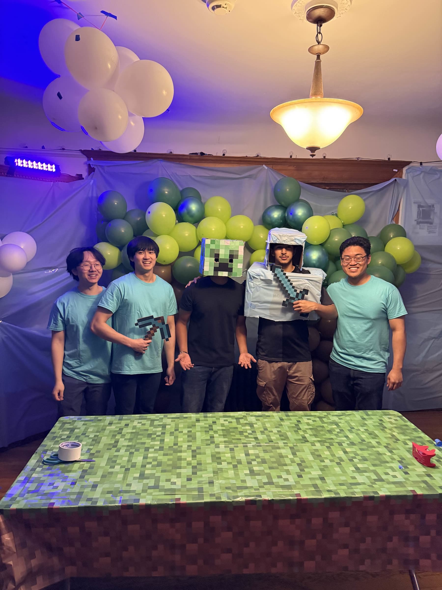 Five people posing behind a decorated table at an indoor event